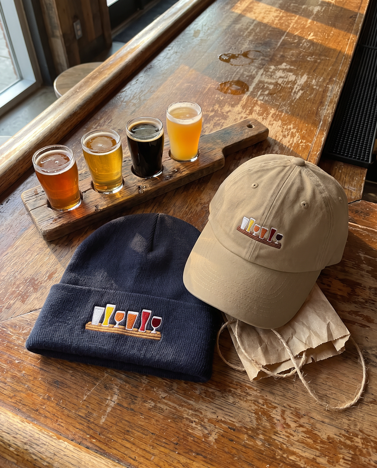The Flight Dad Hat and Flight Cuffed Beanie gift set on a wooden bar top next to a beer flight