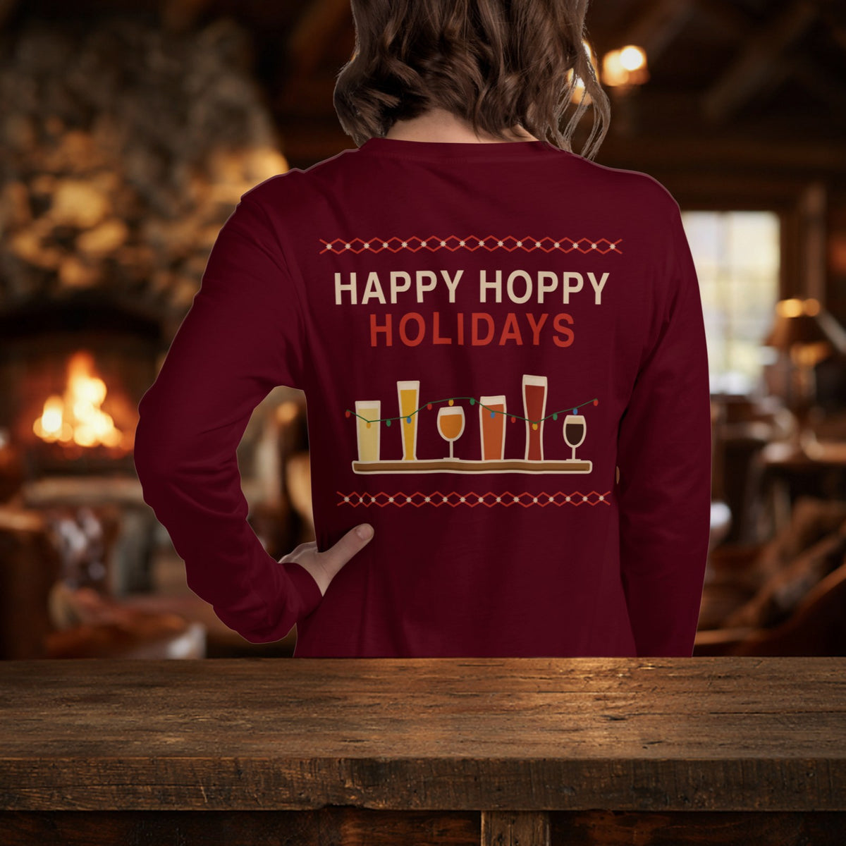 Woman wearing the maroon Christmas Flight long sleeve showing the Happy Hoppy Holidays back design by a lodge fireplace