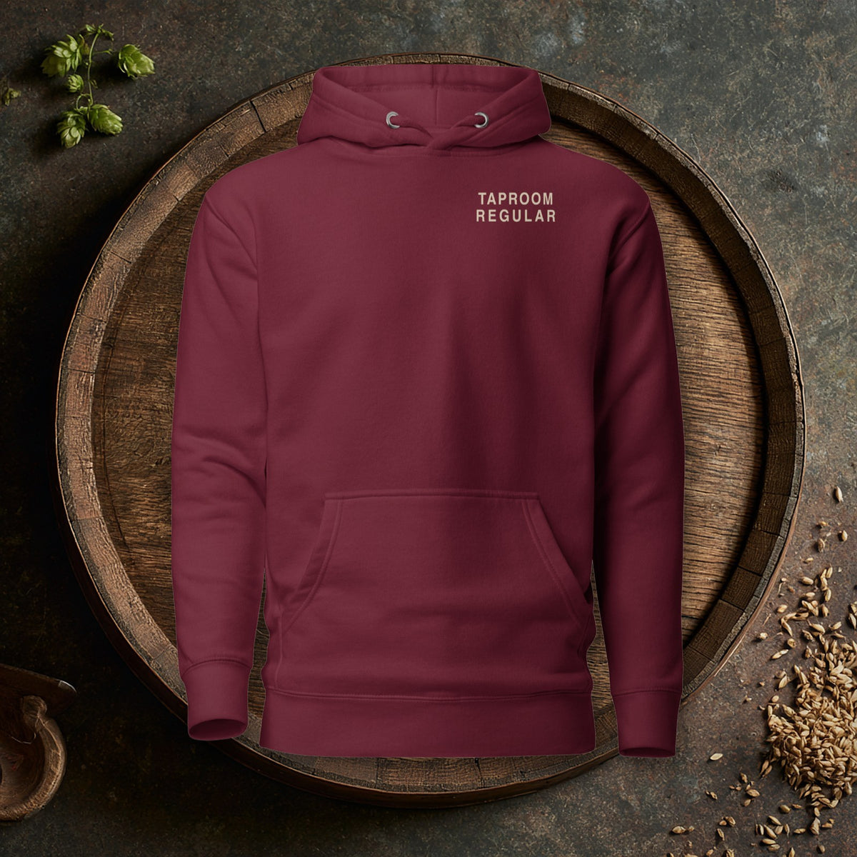 Taproom Regular Hoodie in Maroon laid flat on an oak barrel top