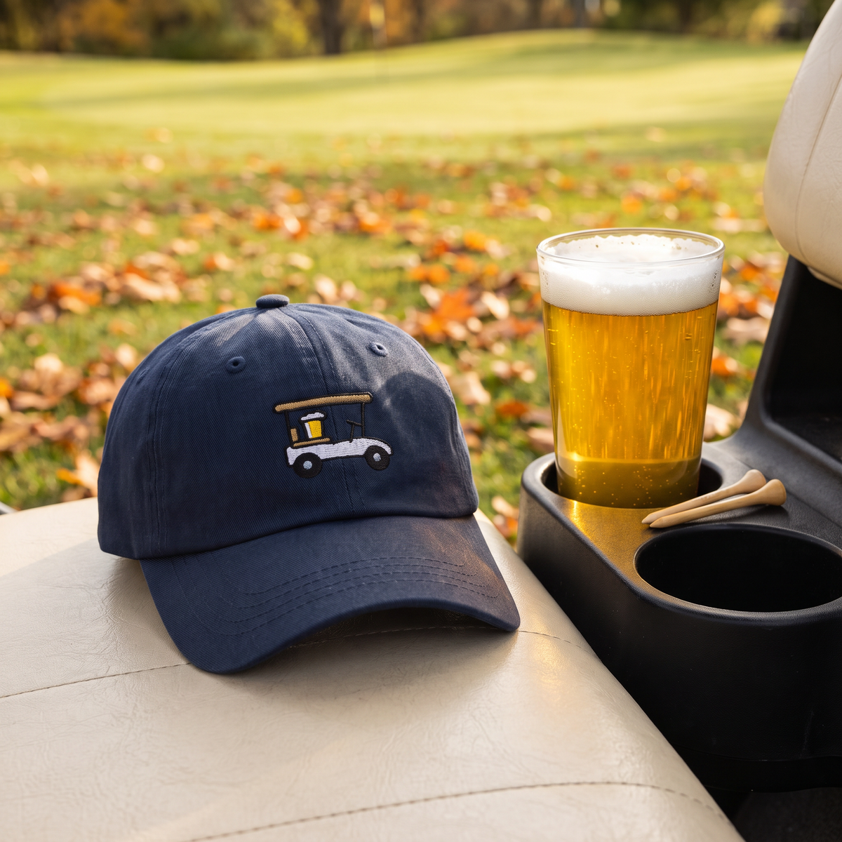Designated Driver Embroidered Golf Dad Hat in Navy on a golf cart seat next to a pint